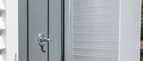A white outdoor storage shed with a sliding door and a metal handle.