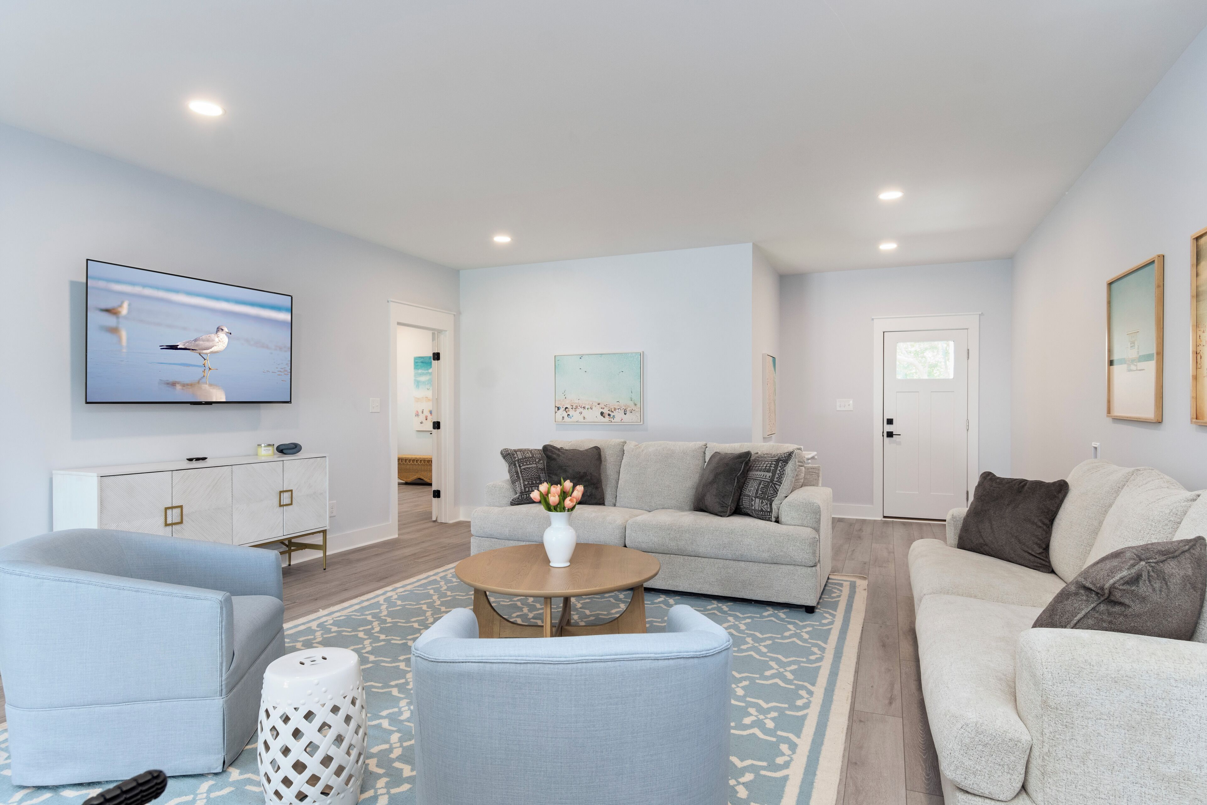 A modern living room with a grey sofa, a coffee table, and a TV mounted on the wall.