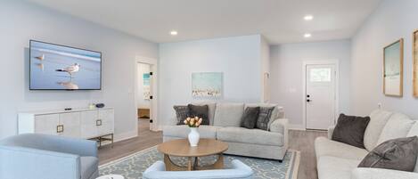 A modern living room with a grey sofa, a coffee table, and a TV mounted on the wall.