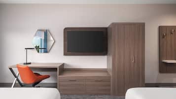 Habitación de hotel con cama, escritorio, silla, televisor montado en la pared y armario.