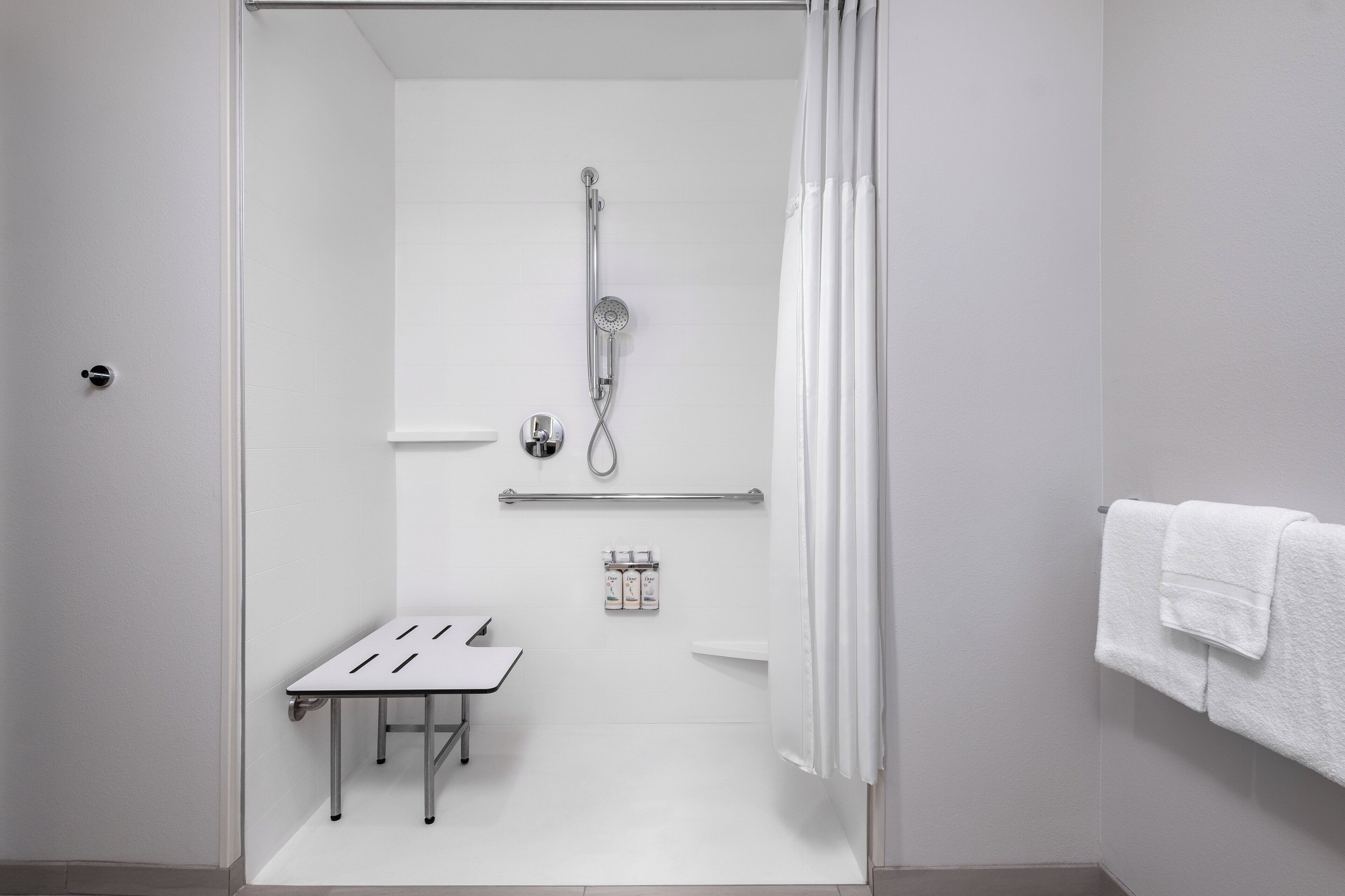 A modern bathroom with a shower, a small table, and a towel rack.