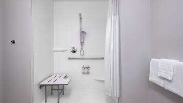 A modern bathroom with a shower, a small table, and a towel rack.