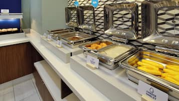 Un bufé con diversas opciones de comida, incluyendo platos calientes, salchicha y una tortilla de queso.