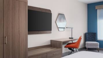 Een moderne hotelkamer met een houten kast, een bureau met stoel, een grote spiegel en een bed.
