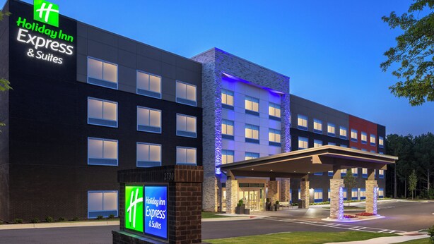 A Holiday Inn Express & Suites building with a modern facade, large windows, and a well-lit entrance area. - Holiday Inn Express & Suites Buford – Mall of Georgia by IHG (Buford)