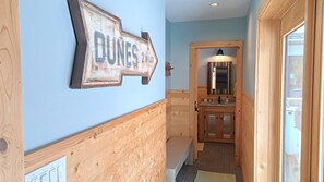 Un pasillo interior de madera con un letrero direccional que indica 'DUNES 2 MILES'.
