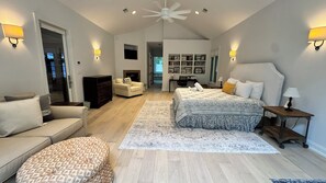A spacious bedroom with a large bed, a sofa, a desk, and a fireplace.