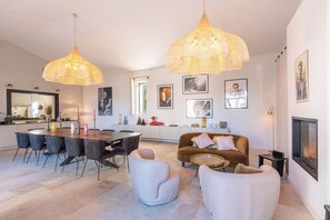 A modern living room with a dining area, featuring a sofa, chairs, a coffee table, and a fireplace.