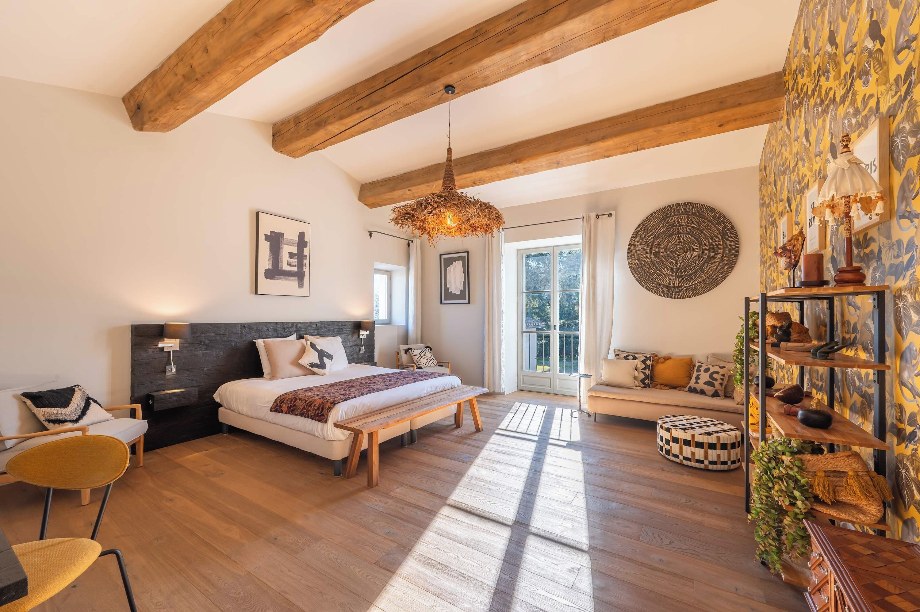 Ein geräumiges Schlafzimmer mit einem großen Bett, einer hölzernen Bank, einer Sitzecke und einem dekorativen Regal.
