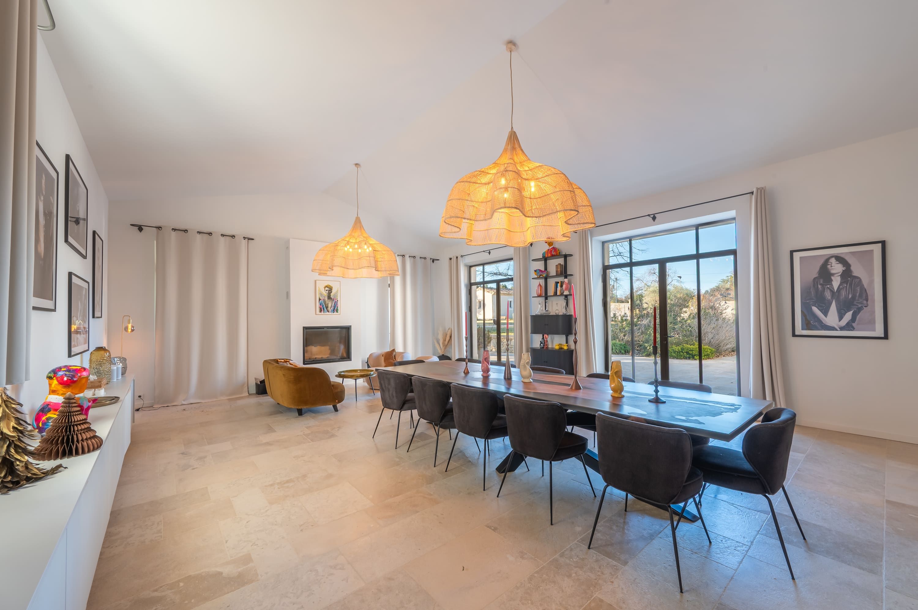 A spacious dining area with a long table, modern chairs, and pendant lighting.