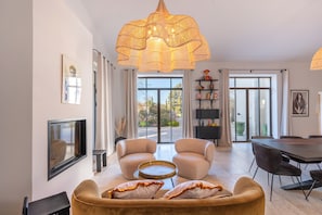 A modern living room with a sofa, chairs, a TV, and a dining area with a table and chairs.