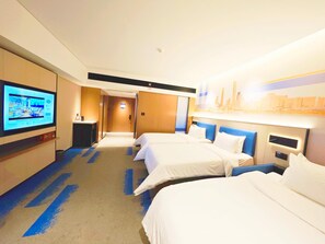 A hotel room with a television, two beds, a desk, and a cityscape painting.