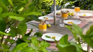 Mesa de jantar ao ar livre com pratos, copos e um castiçal amarelo como centro.