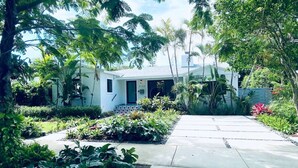 Uma casa moderna com um jardim bem cuidado, um caminho de concreto até a entrada e o número 2150 na porta.