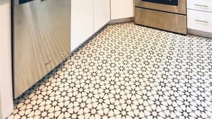 Uma cozinha moderna com armários brancos, micro-ondas, forno e lava-louças.