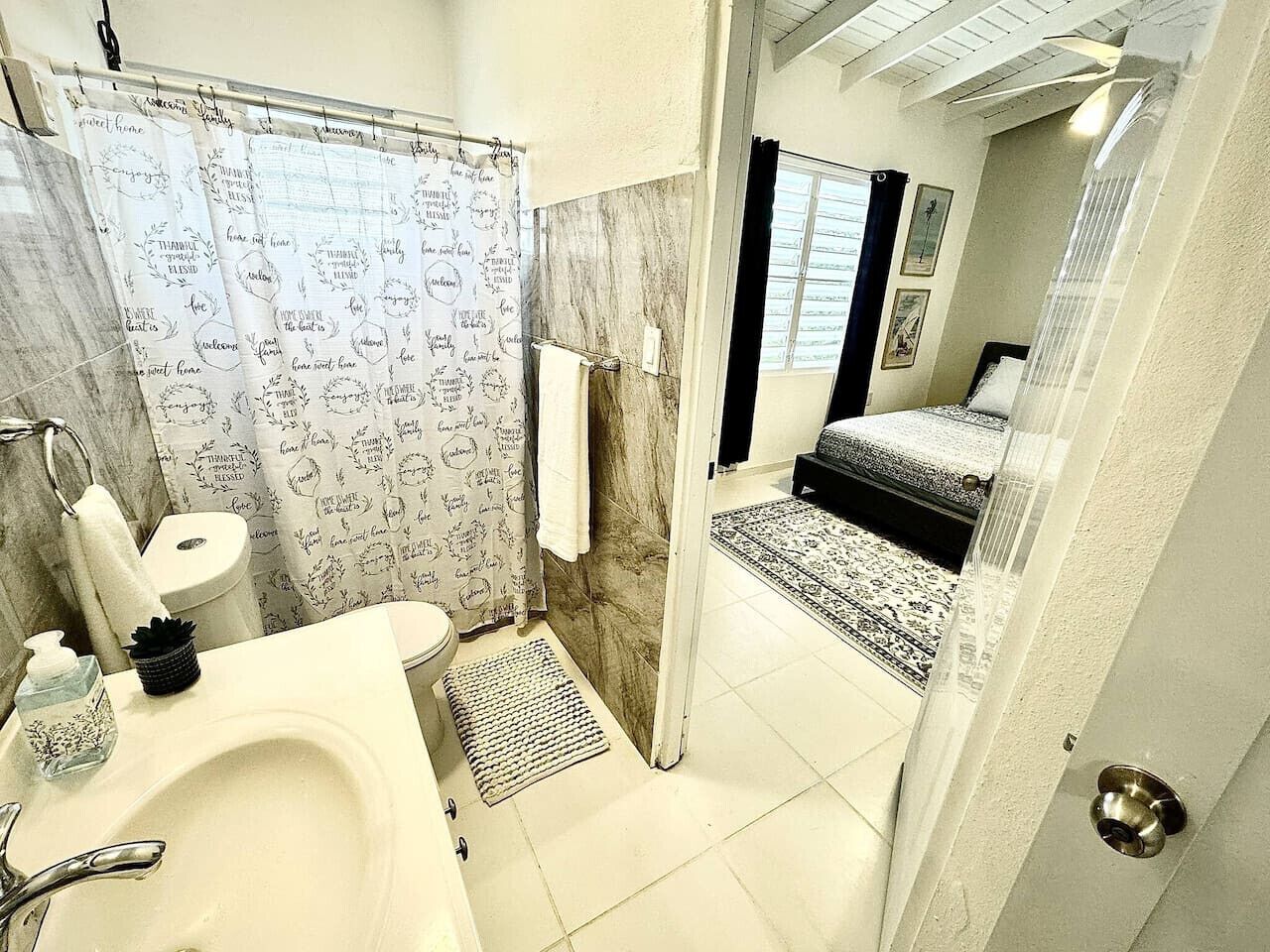 Ein Badezimmer mit Waschbecken, Toilette und Duschvorhang mit motivierenden Sprüchen.