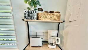 Une étagère de cuisine avec un panneau décoratif sur le thème du café, un grille-pain, une machine à café et un panier de grains de café.