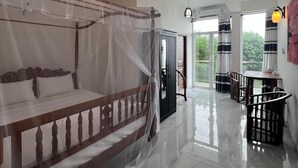 Een ruime kamer met een groot bed, een zithoek en uitzicht op groen.