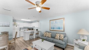 Ein modernes Wohnzimmer mit einem grauen Sofa, einem weißen Couchtisch und einem Deckenventilator.