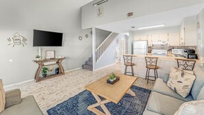 Ein modernes Wohnzimmer mit Couch, Fernseher an der Wand und einem Couchtisch aus Holz.