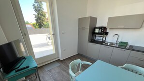 Una cocina compacta con comedor, televisor y control remoto sobre una mesa.