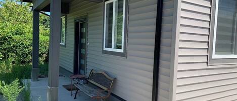 A house with a covered porch, a bench, and a window.