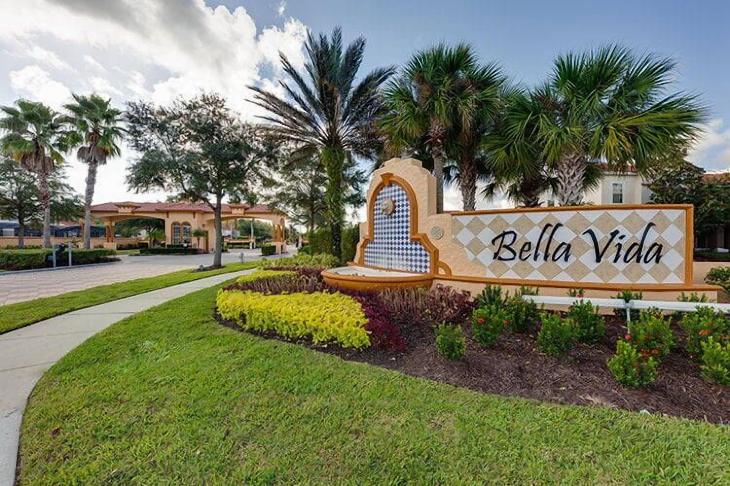 A sign for Bella Vida with a tiled archway and a landscaped garden.