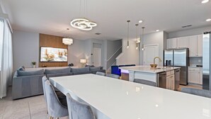 Een moderne keuken met een centraal kookeiland, inbouwapparatuur en een eethoek met barstoelen.