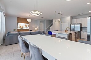 Una cocina moderna con una isla central, electrodomésticos integrados y un comedor con taburetes de bar.