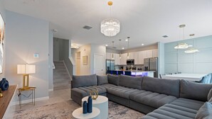 Een moderne woonkamer met een modulaire bank, een ronde salontafel en een kroonluchter.