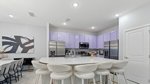Une cuisine moderne avec un îlot central, des tabourets de bar et des meubles de couleur violette.