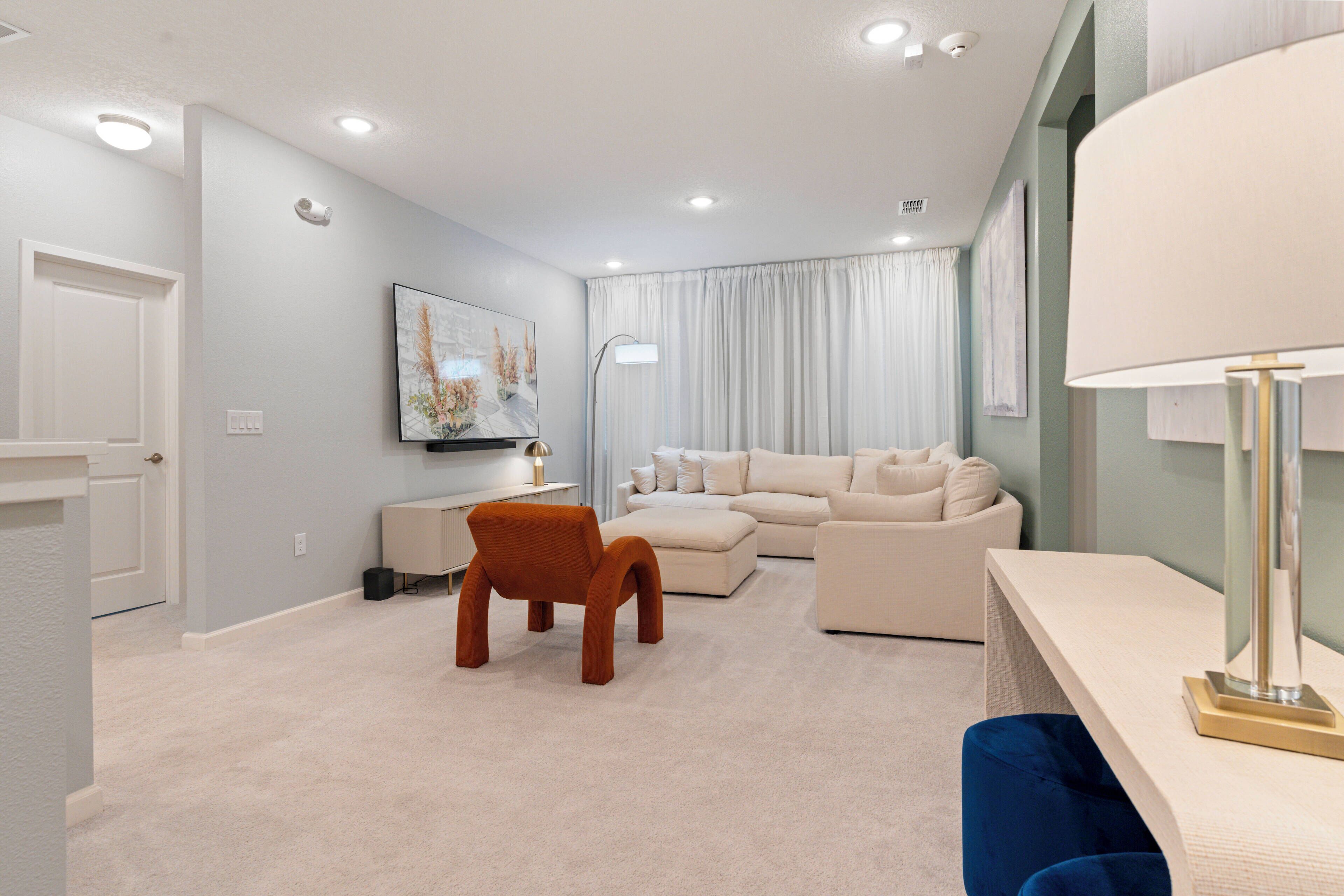 A modern living room with a sofa, armchair, and a desk with a lamp.