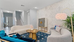 Un salon moderne comprenant un canapé, des fauteuils, une table basse et un élément décoratif mural.