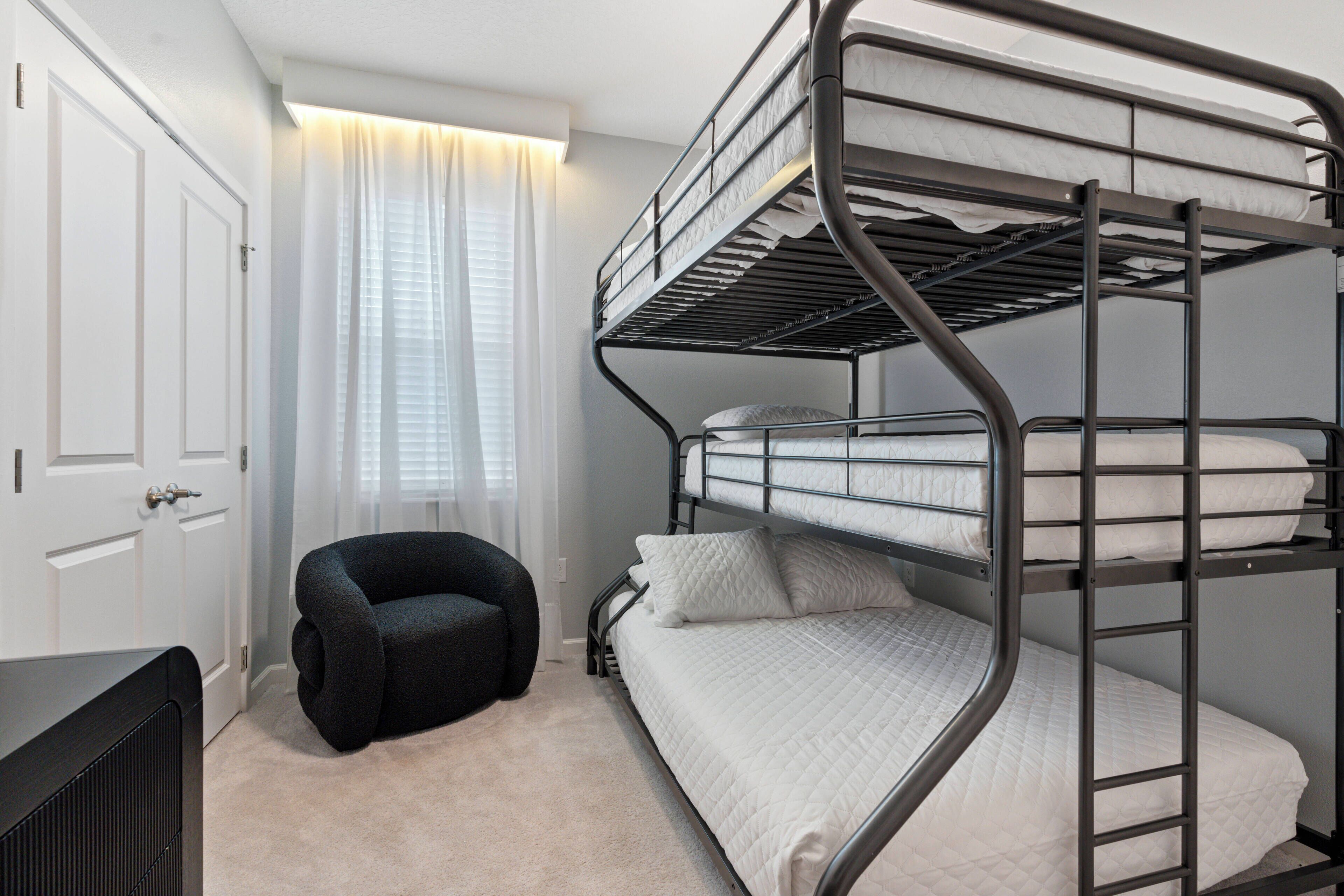 Una camera con un letto a castello, una sedia nera e un termosifone.