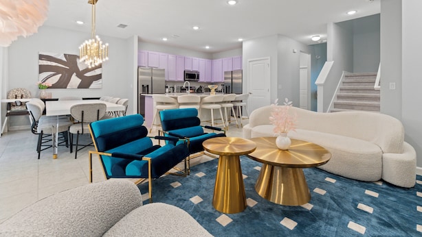 Un salon moderne comprenant un canapé, des fauteuils bleus, une table basse et un coin repas avec une table et des chaises.