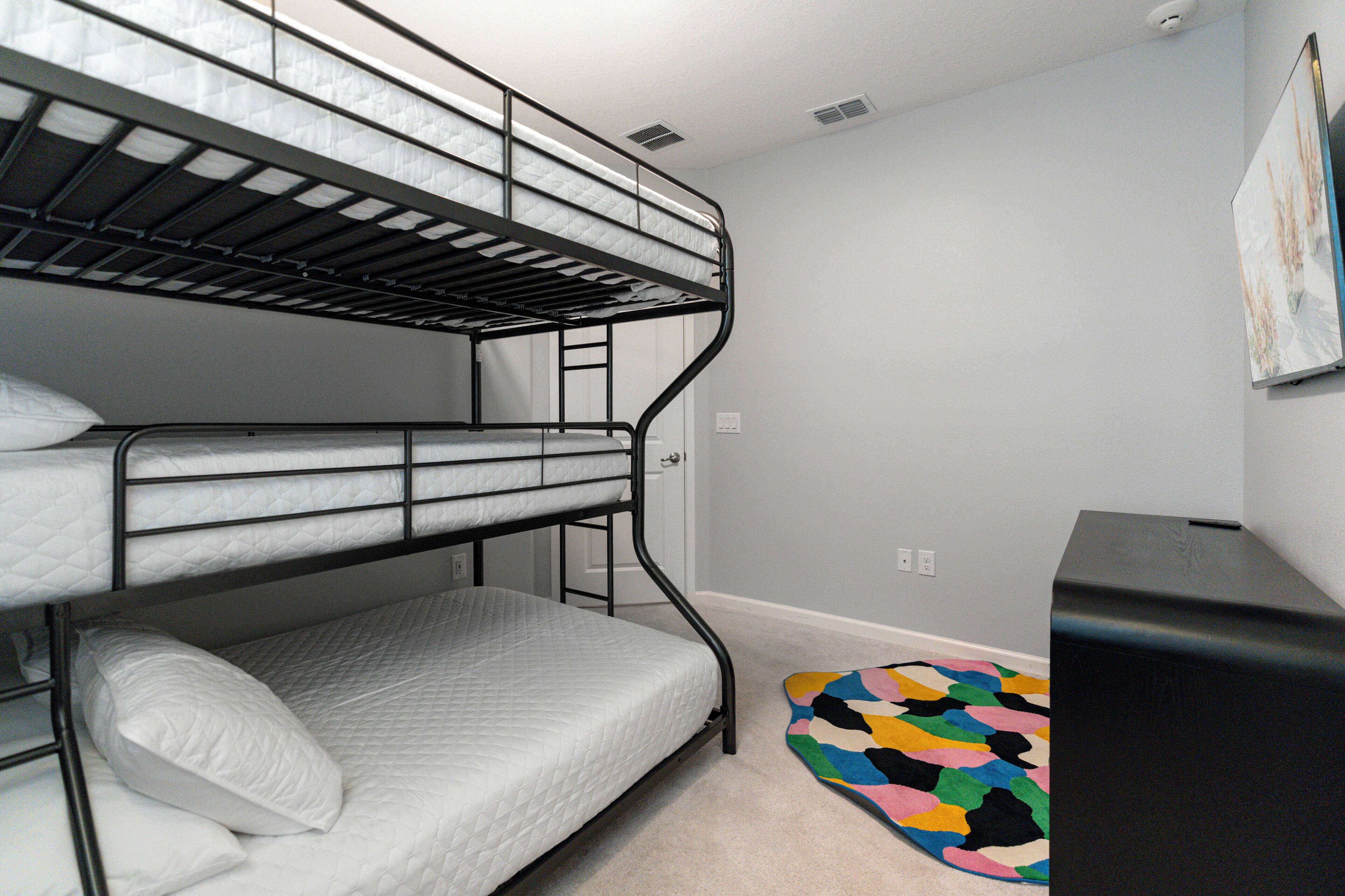 Quarto com beliche, tapete colorido e um alto-falante preto.