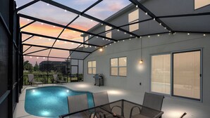 An outdoor pool area with a glass enclosure, seating, and a barbecue grill.