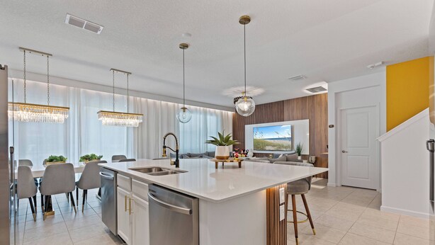 A modern kitchen with a central island, stainless steel appliances, and pendant lighting.