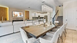 Una cocina moderna con una isla grande, muebles blancos y una lámpara de araña.