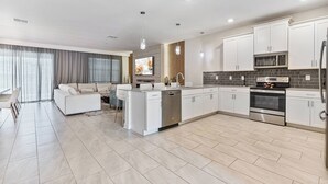 Una cocina moderna con armarios blancos, horno de acero inoxidable y microondas integrado.