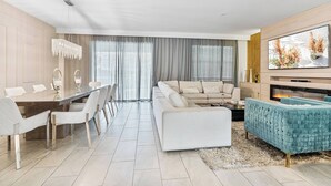 Una sala de estar moderna con comedor, un sofá, un televisor y una chimenea.