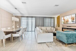 Uma sala de estar moderna com área de jantar, sofá, televisão e lareira.