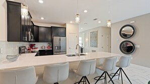 A modern kitchen with a large island, bar stools, dark cabinets, and pendant lighting. - 9BR house sleeps 22 with private pool in kissimmee (Kissimmee)