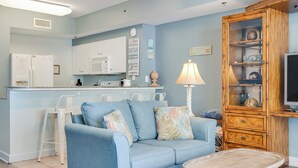 Ein Wohnzimmer mit einem blauen Sofa, einer Holzkabine und einer Küche im Hintergrund.