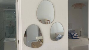 Ein Zimmer mit weißer Wand, einer Tür zu einem Badezimmer und einem Bett mit weißem Kopfteil.