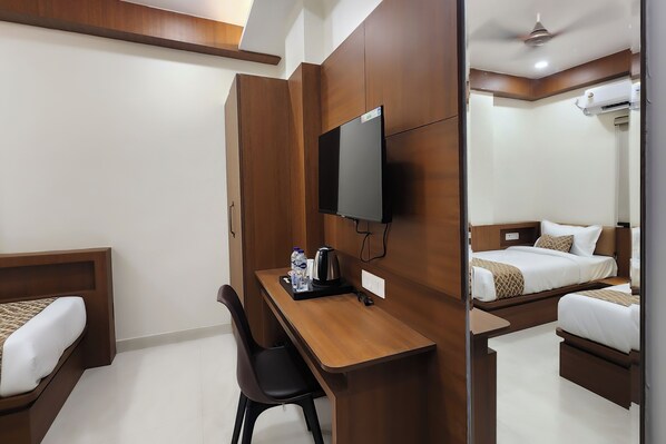 Une chambre d’hôtel avec un bureau en bois, une télévision, un lit et une chaise.