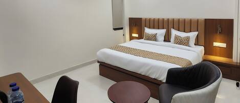 A hotel room with a bed, bedside table, chair, and a small round table.
