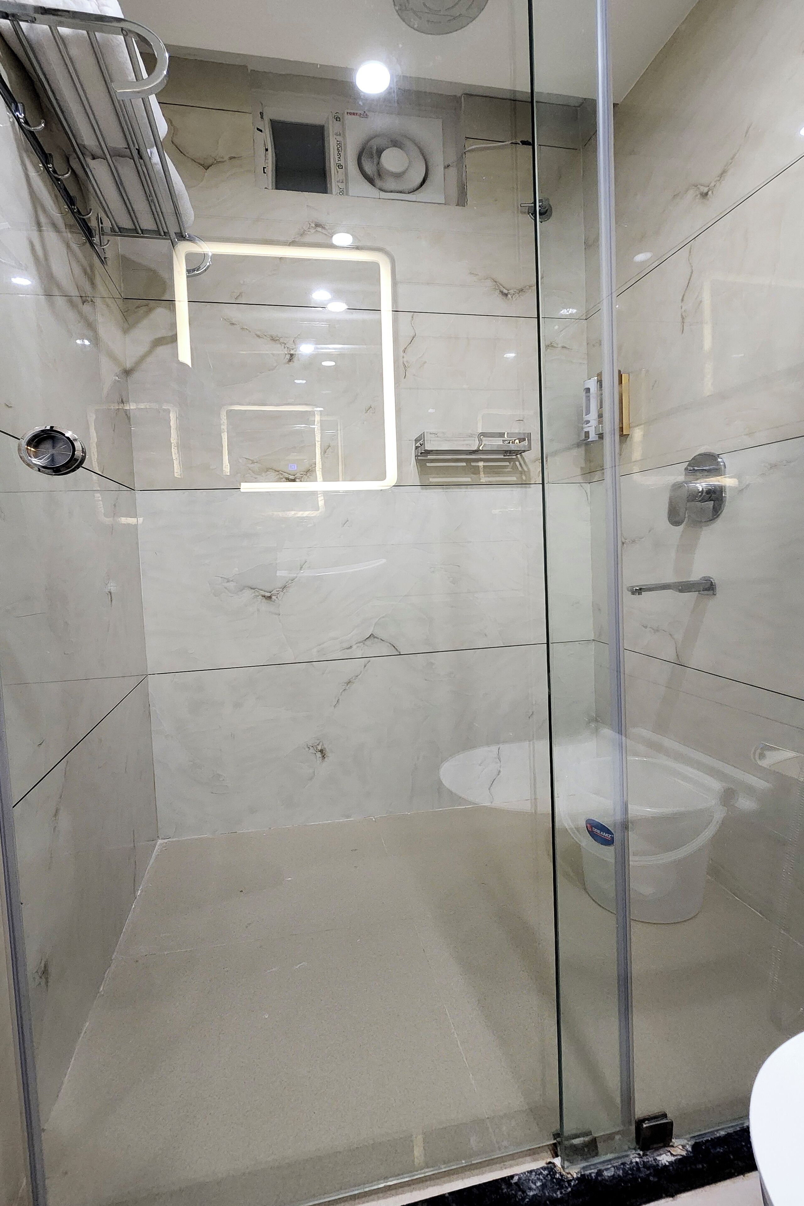 Et moderne badeværelse med et glasafskærmet brusebad, marmortile og et fritstående toilet.