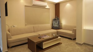 A modern living room with a beige sofa, a glass coffee table, and a decorative statue. - Kashi Vilaa (Varanasi)