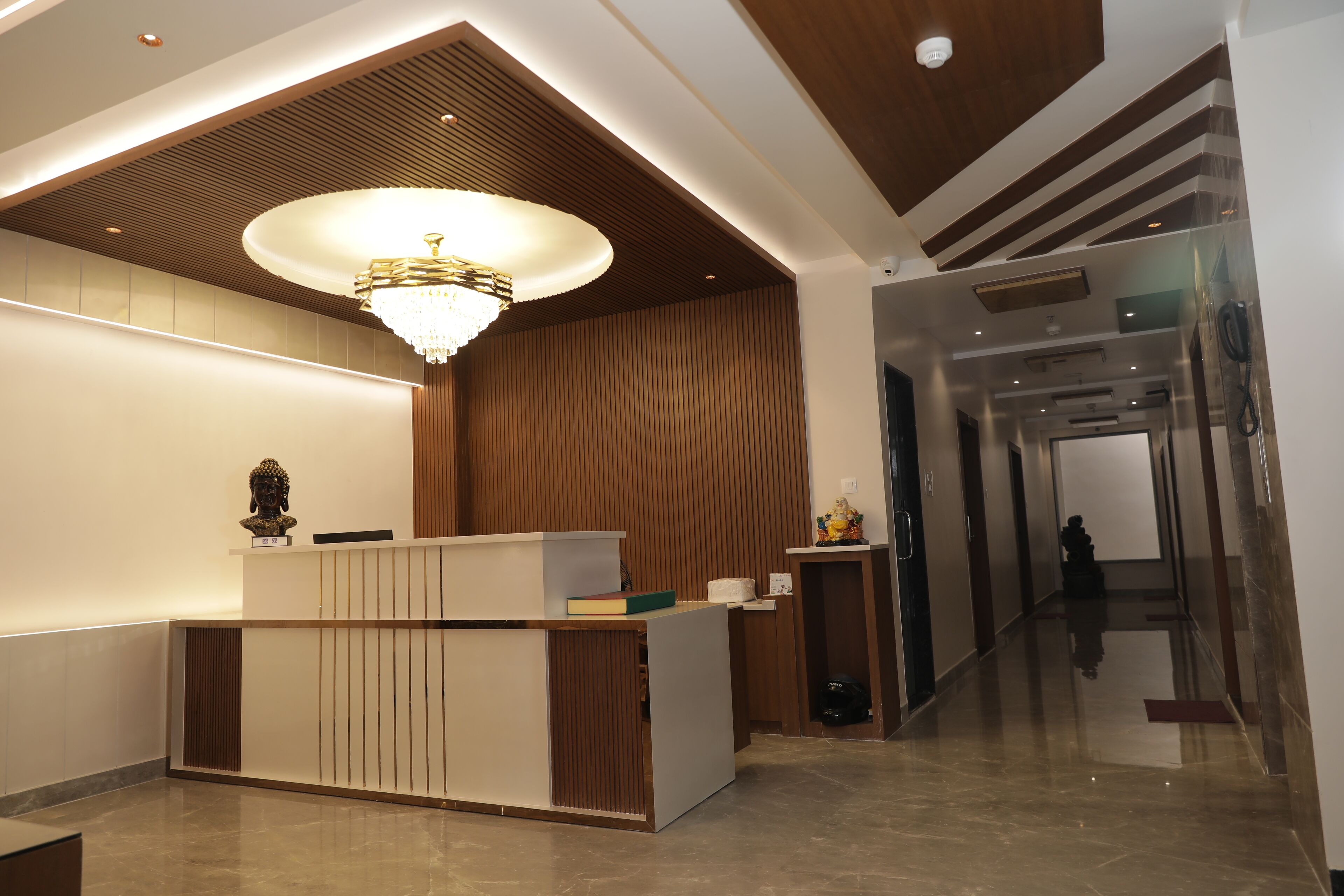 A reception desk with a modern design, a chandelier, and a wooden panel wall.